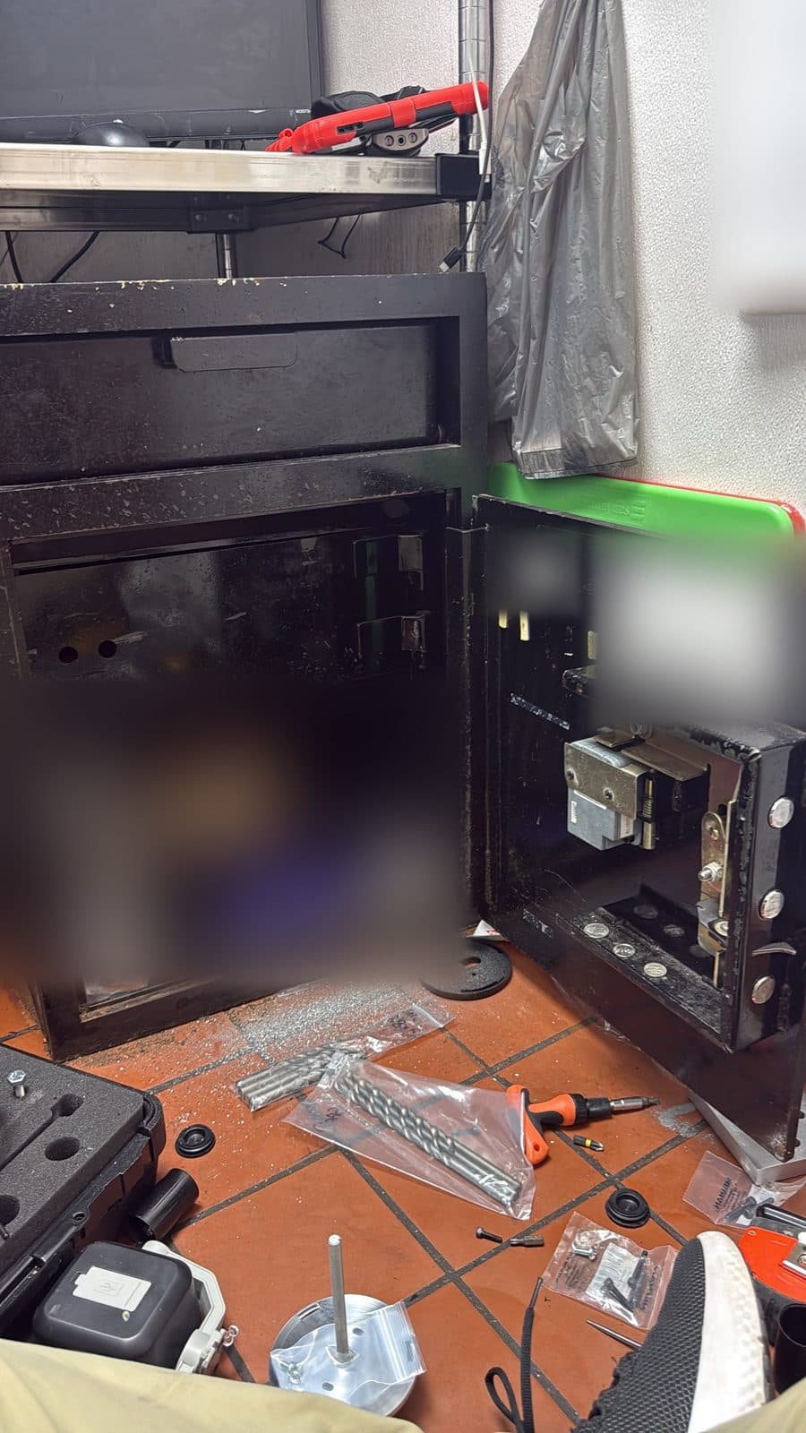 A depository safe opened, tools laid out on the floor