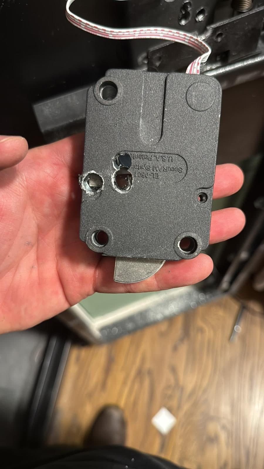An electronic safe lock held in hand after removal